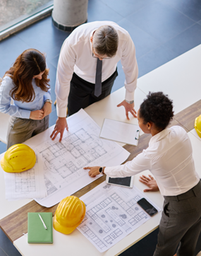 people looking over blueprints on a desk